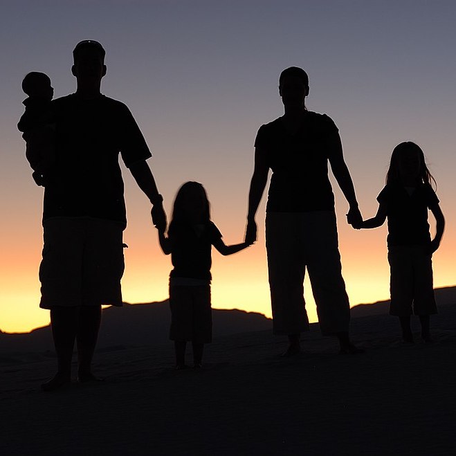 portrait of a family silhouetted near a sunset